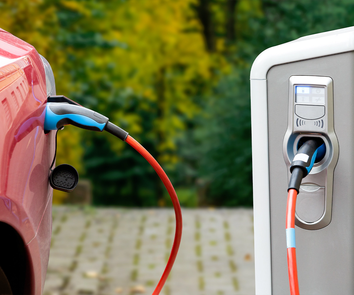 A pink car is plugged into an electric vehicle charger.