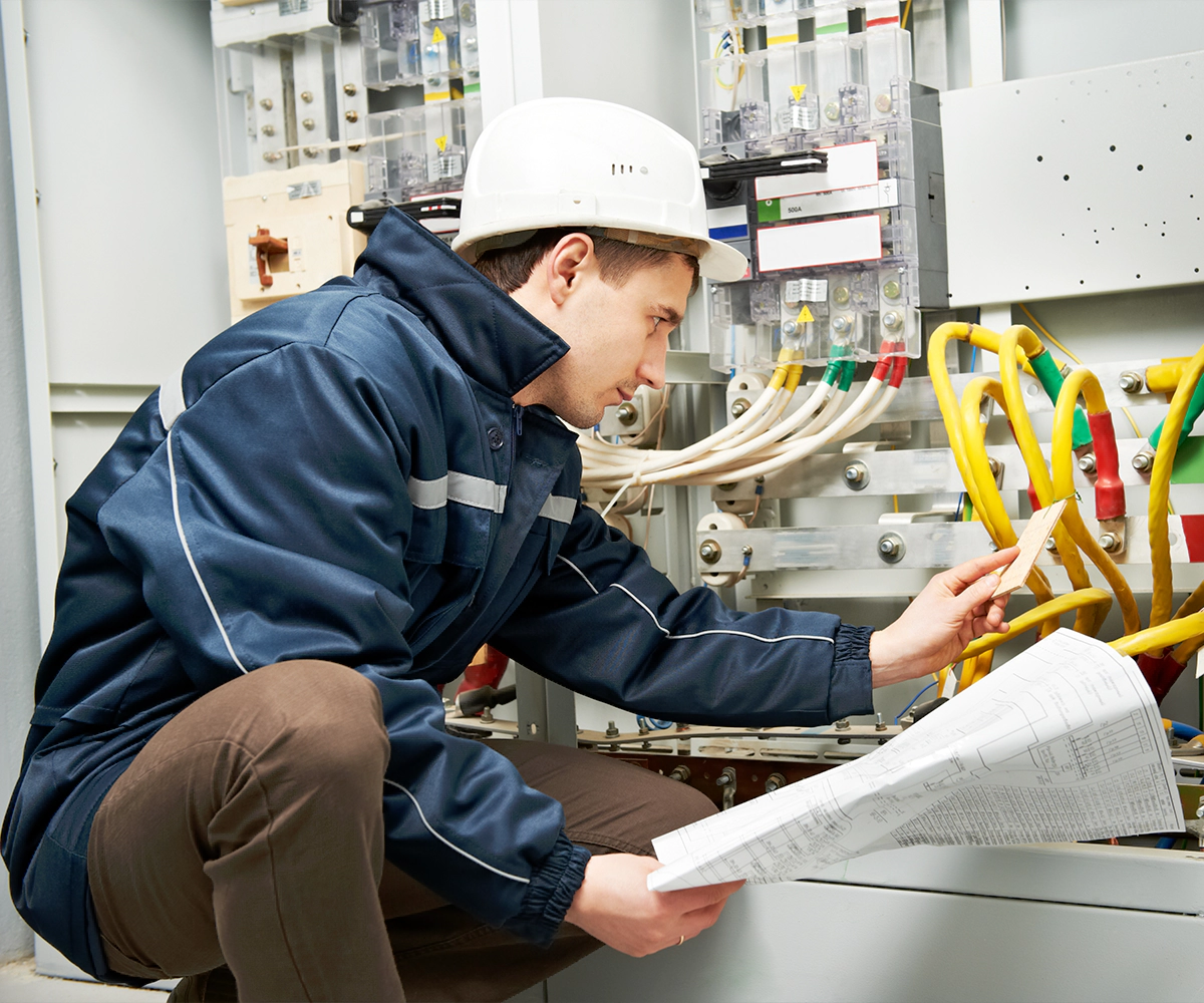 A man in blue jacket and white hard hat working.