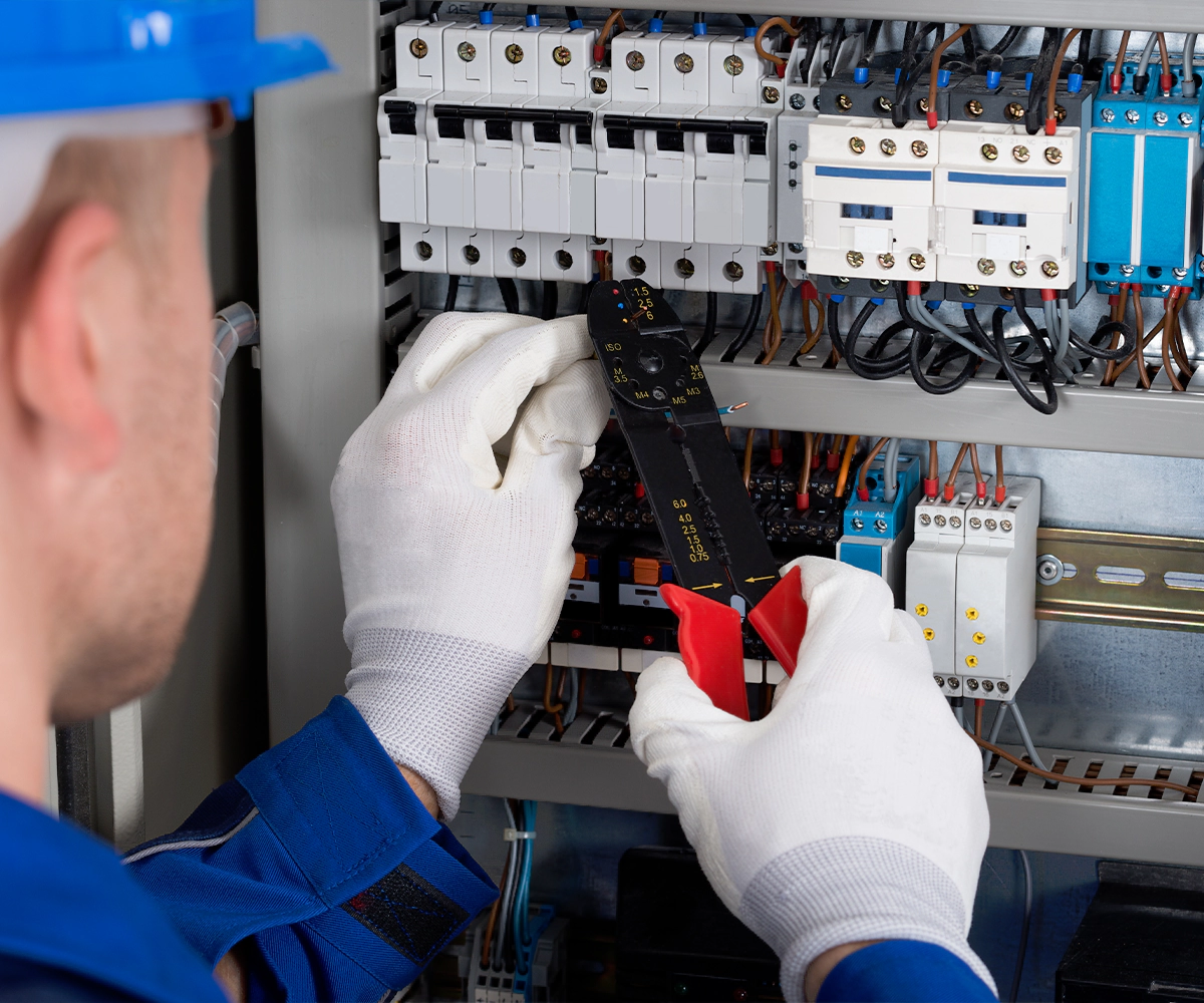 A man holding a pair of scissors in front of an electrical panel.