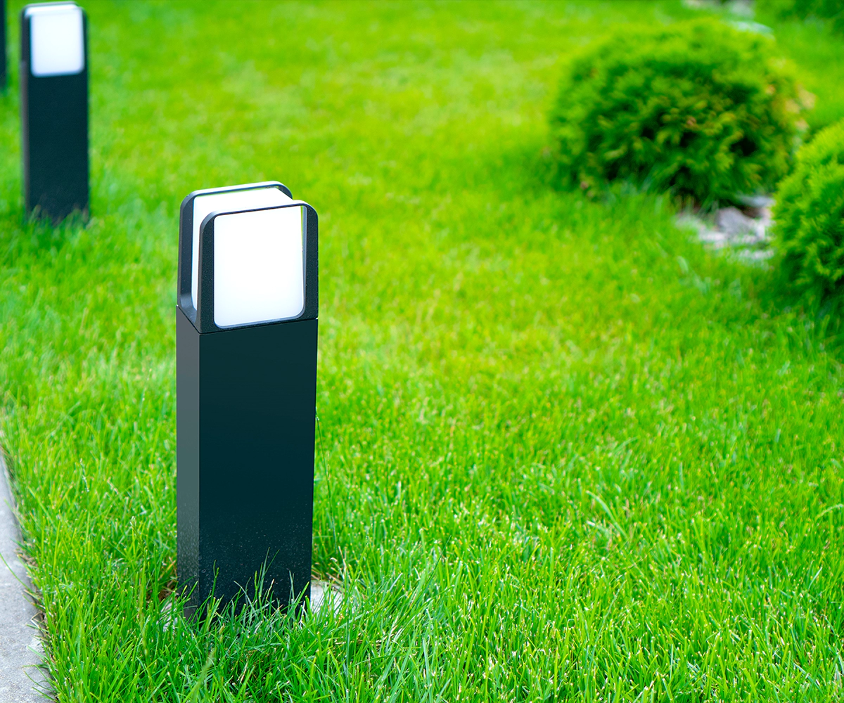 A group of lights in the grass near some bushes.