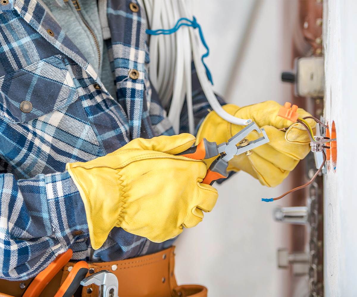 A person in yellow gloves holding a pair of scissors.