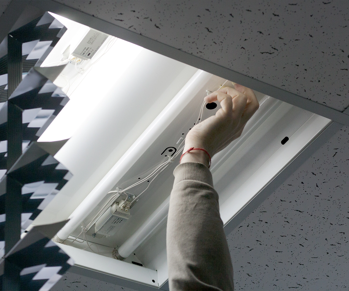 A person is holding onto the ceiling of an office.