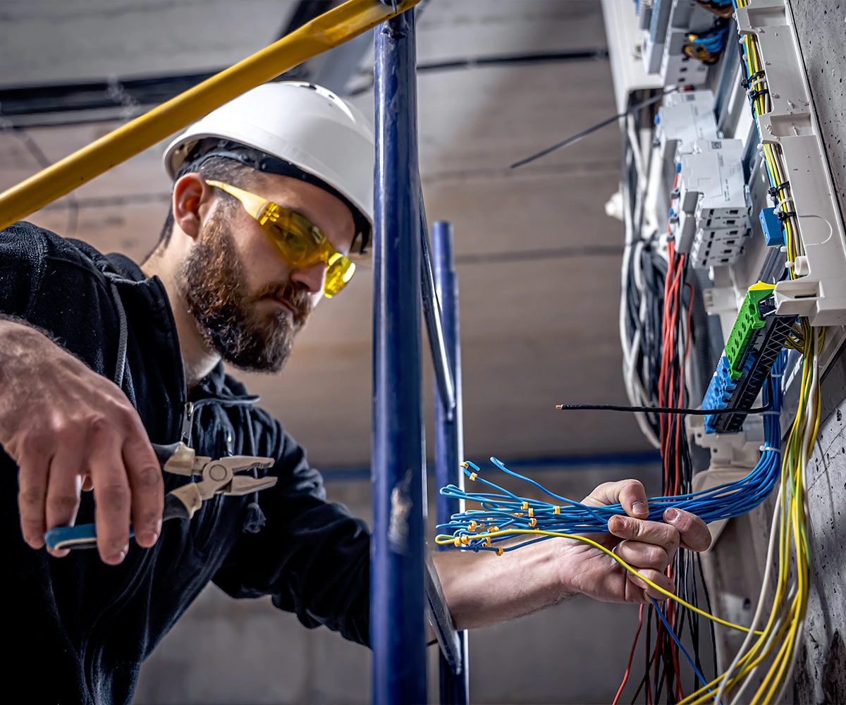 A man working on wires in an electrical room.