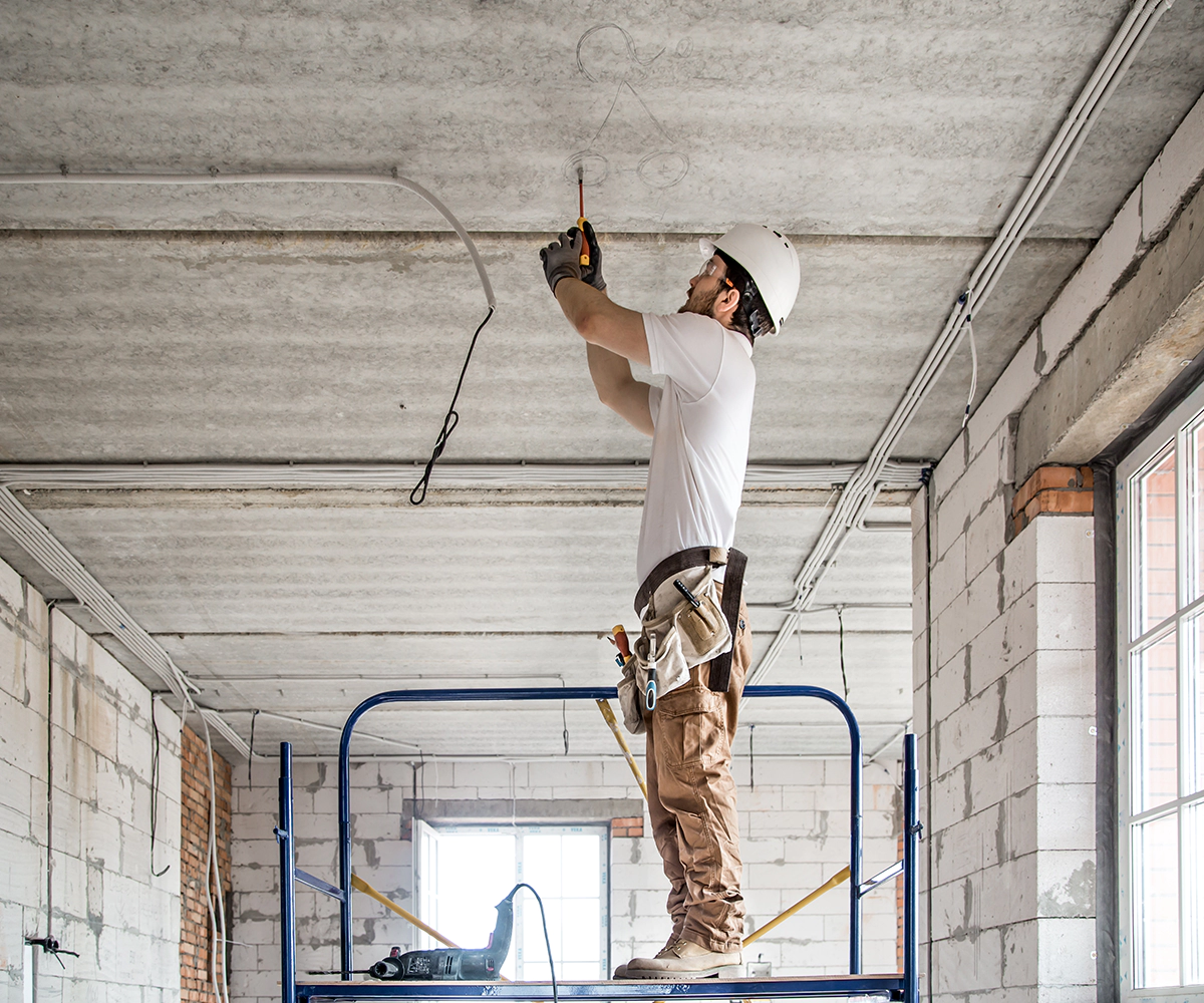 A man standing on top of a blue scissor lift.