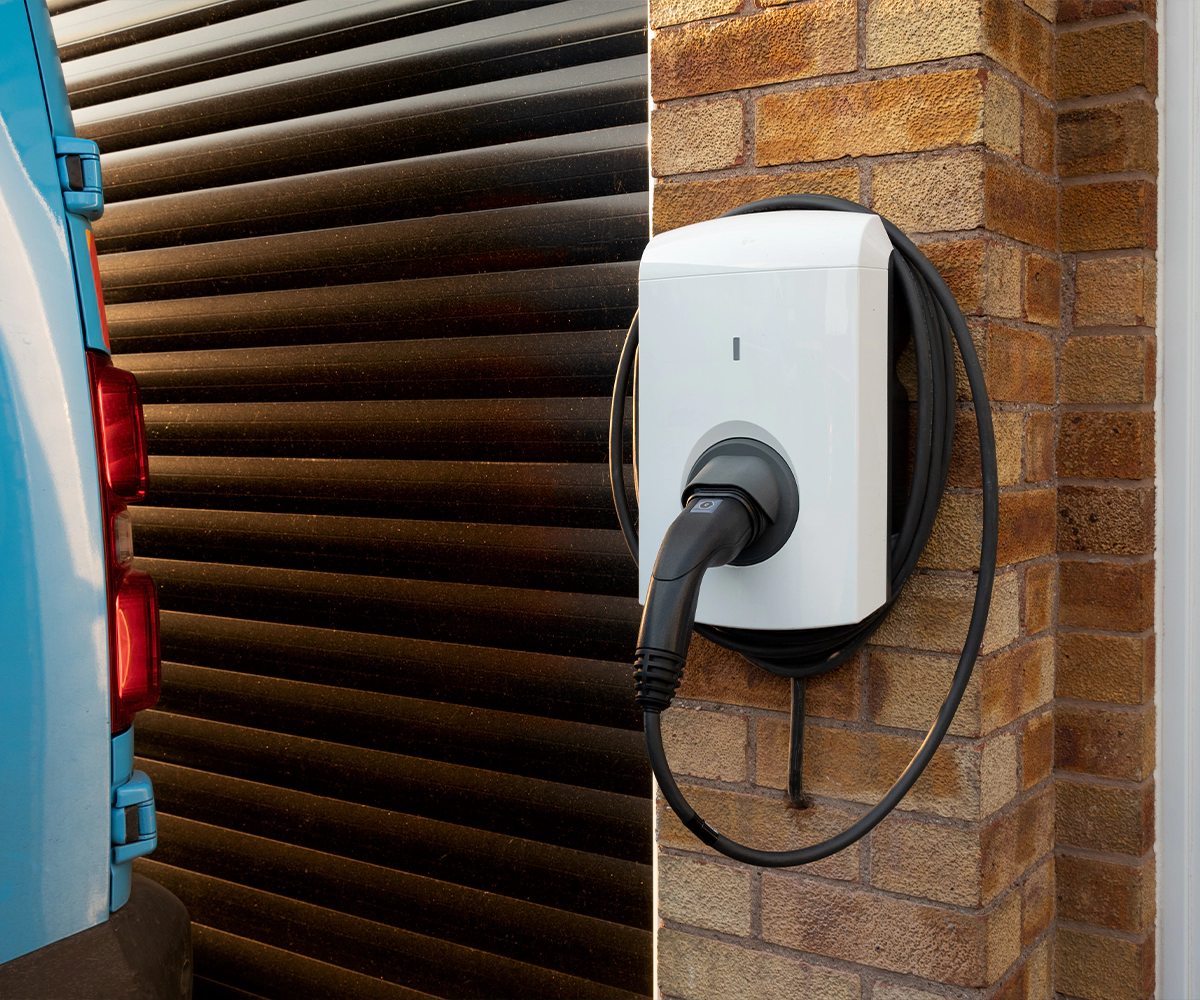 A white electric car charger attached to the side of a building.