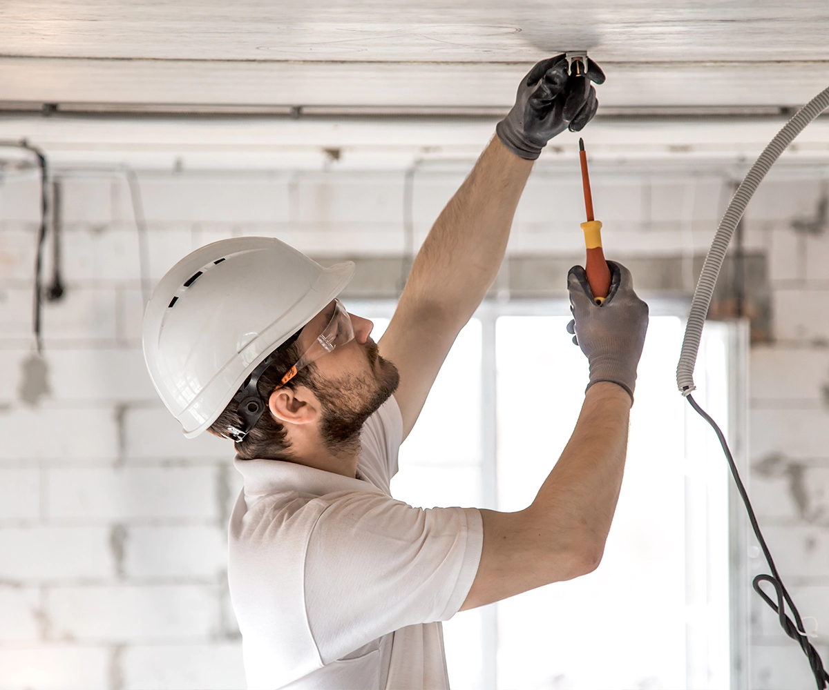 A man in white shirt holding a screwdriver.