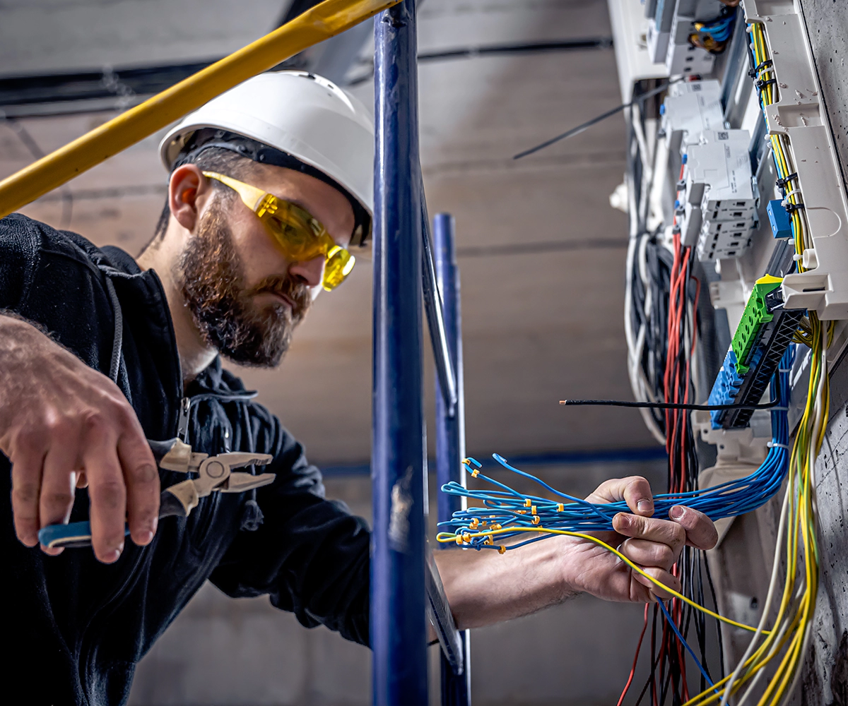 A man working on wires in an electrical room.