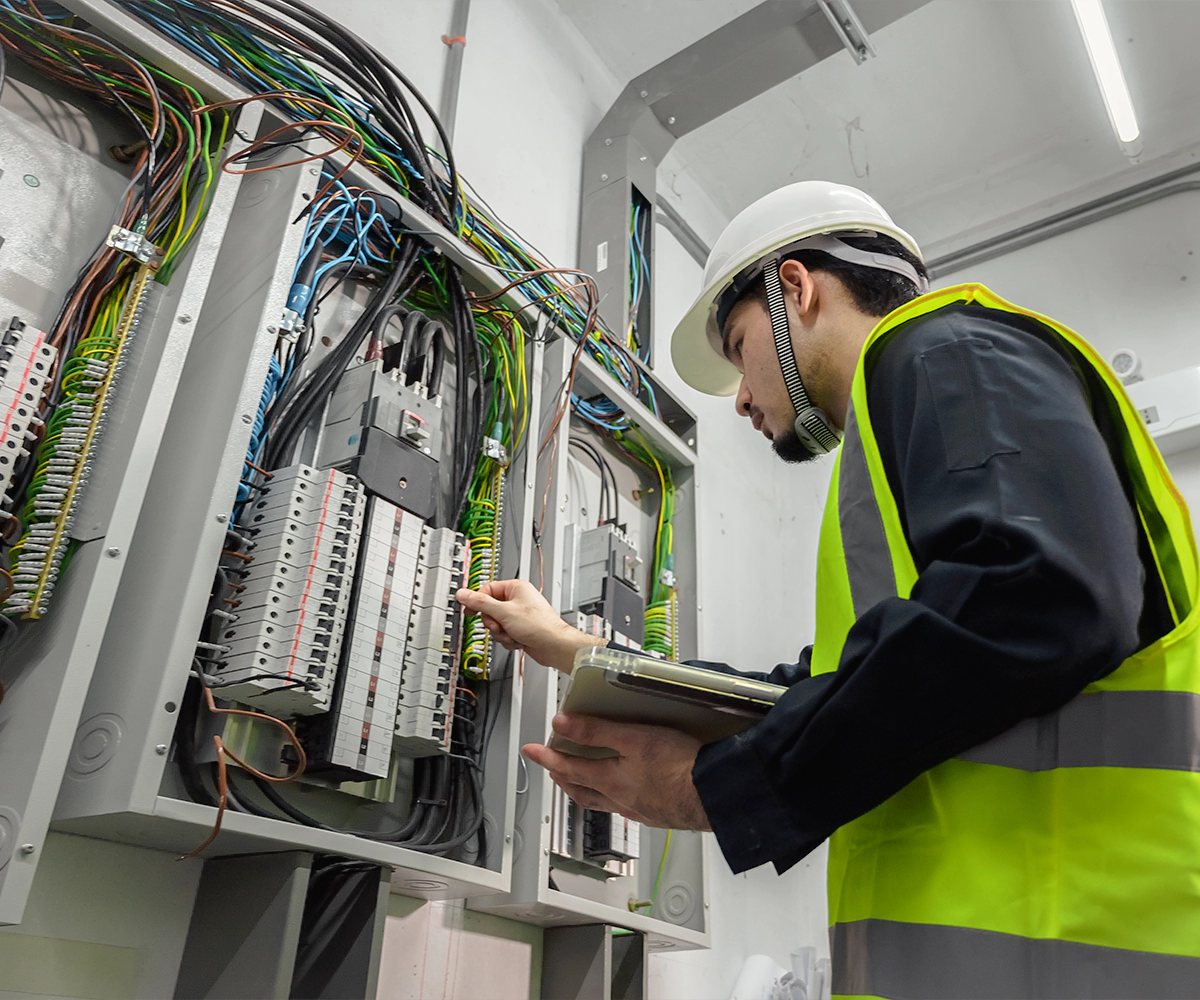 A man in safety vest looking at electrical equipment.