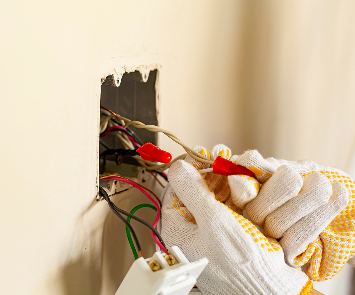 A person is working on the wires of an electrical outlet.