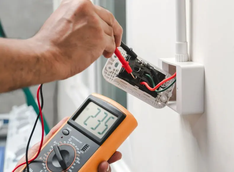 A person is holding an electrical meter and testing it.